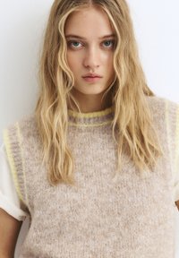 Kurzärmliger Strickpullover mit einem flauschigen, hellbeigen Textur und kontrastierenden gelben Abschlüssen an Hals und Ärmeln.