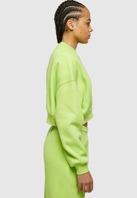 Felpa corta e pantaloni abbinati in un vivace verde lime. Realizzati in un materiale morbido, con maniche lunghe e vita elasticizzata.