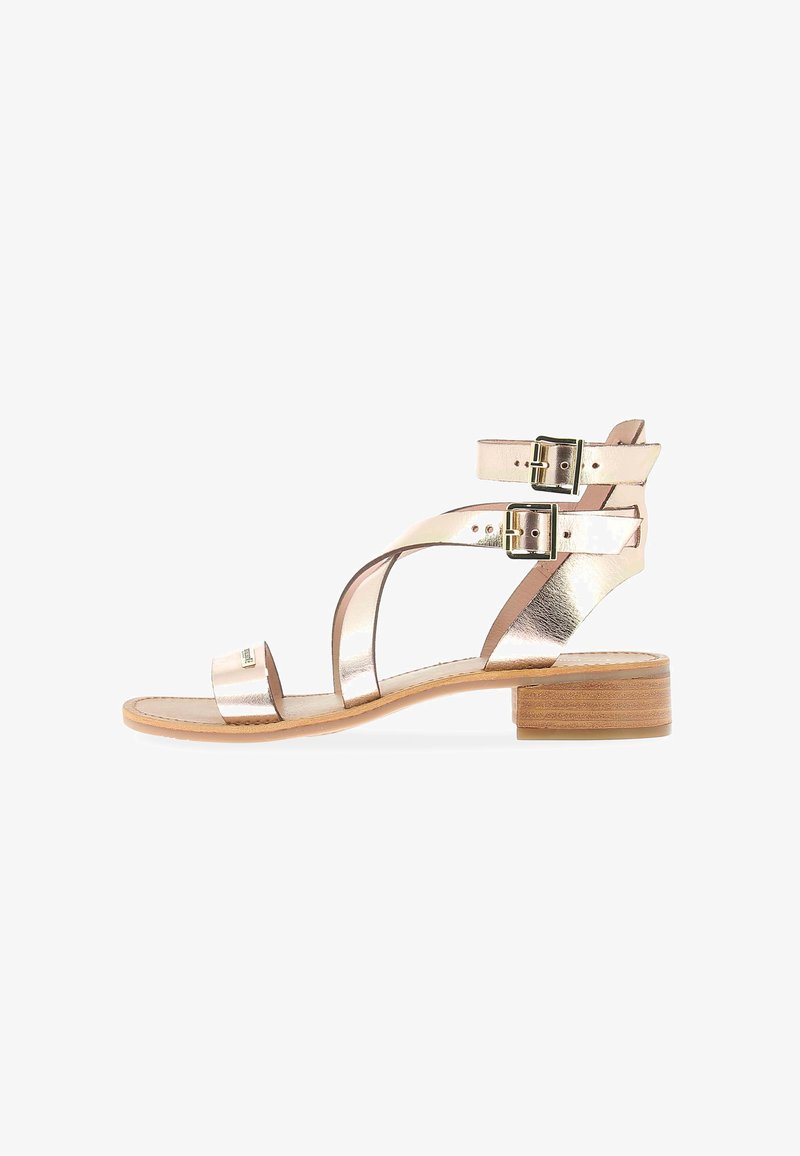 Sandalias metálicas rosas con un bajo tacón cuadrado, que cuentan con hebillas dobles ajustables y tiras entrelazadas. Parte superior de piel suave con una suela natural.