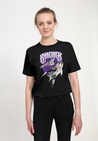 Černé bavlněné tričko s barevným motivem postavy Shreddra v akční póze, s fialovými akcenty a stylizovaným textem.