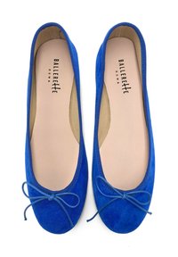 Bailarinas azul suede con puntera redonda, textura suave y un lazo en la parte delantera. El interior cuenta con un forro beige.