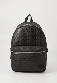 Mochila preta com padrão de logotipo em relevo, formato arredondado, alça superior, fecho com zíper e bolso frontal com zíper, adornos em prata.