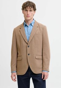 Brauner strukturierter Blazer mit zwei Fronttaschen, einer Brusttasche und schwarzen Knöpfen, kombiniert mit einem hellblauen Hemd.