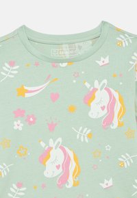 Ανοιχτό πράσινο βαμβακερό μπλουζάκι με λευκούς μονόκερους με ροζ και κίτρινες λεπτομέρειες, περιτριγυρισμένους από αστέρια, καρδιές και ανθικά μοτίβα.