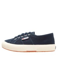 Marineblå kanvas sneakers med rund tå, hvit gummisåle, seks snørehull og en liten Superga-logo på siden. Strukturert overflate.