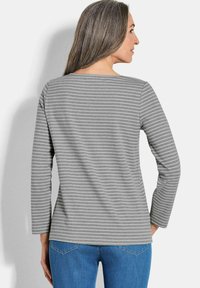 Grau langärmliges Shirt mit dünnen weißen horizontalen Streifen, mit Rundhalsausschnitt und entspanntem Schnitt, kombiniert mit blauen Jeans.