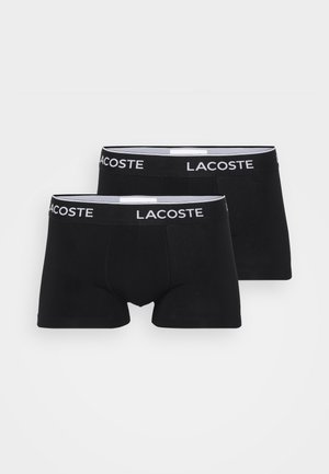 Boxer briefs pretos com uma textura suave e uma cintura elástica, apresentando o logotipo "LACOSTE" em branco. Dois pares estão expostos.