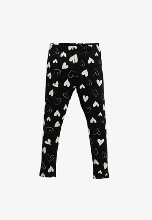 Leggings negras con un patrón de corazones blancos, confeccionados en una tela suave con una cintura elástica para mayor comodidad. Ajuste slim y largo completo.