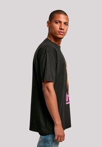 Black graphic t-shirt with short sleeves, featuring a vibrant print and contrast color design. Loose fit with a round neckline.