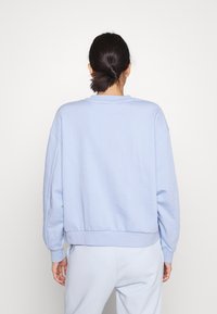 Felpa azzurra chiaro con scollatura rotonda, spalle scese e polsini a costine. Tessuto morbido e vestibilità rilassata; indossata con pantaloni abbinati azzurri chiaro.