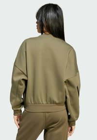 Olivovo zelená mikina so štruktúrovaným povrchom, spustenými ramenami a rebrovaným lemom. Kombinujte ju so zodpovedajúcimi nohavicami pre úplný vzhľad.