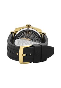 Gold-tone stainless steel watch with a black rubber strap. Patterned dial and a round case. Features a crown and buckle closure.