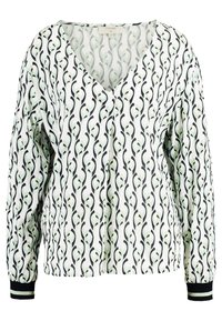 Blouse à manches longues en crème avec un motif de feuilles noires et vertes. Présente un col en V et des poignets élastiques avec des accents noirs. Tissu texturé.