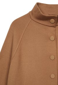 Veste en tricot marron avec col montant et quatre boutons-pression ronds le long du devant.