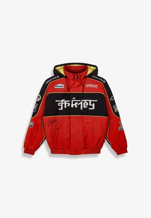 Rood en zwart jack met capuchon, voorzien van gele accenten, meerdere patches, zichtbare ritsen en een handtekening op de voorkant.