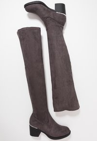 Botas por encima de la rodilla en ante sintético gris, con tacón recto y textura suave, y un detalle metálico pulido en el tacón.