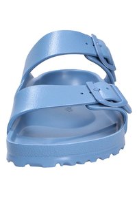 Sandal in plastica azzurra chiara con due cinturini regolabili dotati di fibbie, suola con texture e una suola sagomata con scanalature rialzate.