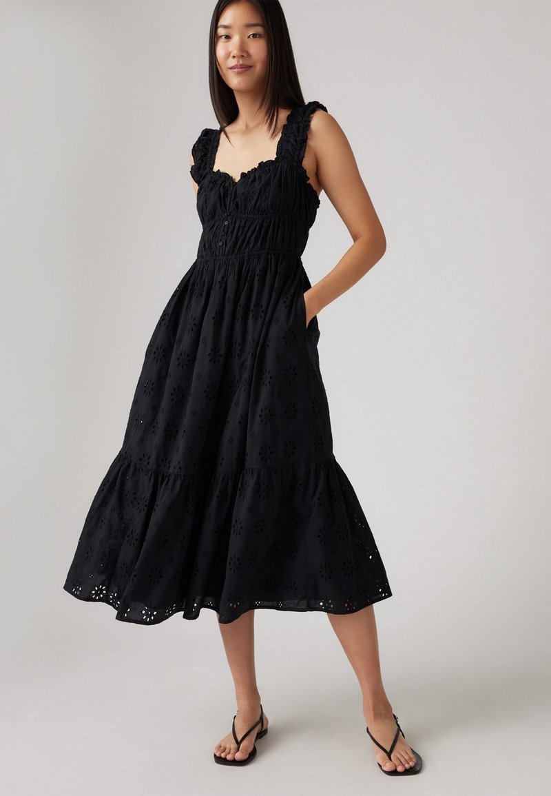 Vestido negro de algodón con escote fruncido, corpete fruncido y falda en capas que presenta patrones florales bordados y bolsillos laterales.