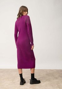 Fialové šaty z pleteniny s ribbed vzorem, dlouhými rukávy a délkou do poloviny lýtek. Mají přiléhavý střih a jednobarevný design.