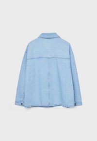 Veste en denim bleu clair avec des manches longues, des poignets à boutons et une couture arrière droite, présentée de dos sur un fond uni.