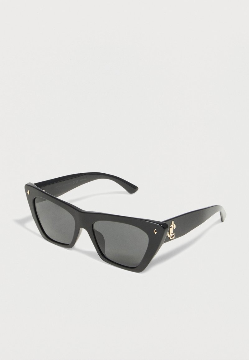 Μαύρα υπερμεγέθη γυαλιά ηλίου με τετράγωνα πλαίσια, σκούρους φακούς και χρυσές λεπτομέρειες σερβιέτας σε λευκό φόντο.