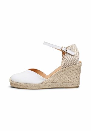 Espadrilla blanca con cuña, tacón de yute tejido, punta cerrada, correa en el tobillo y sección trasera texturizada con cierre de hebilla.