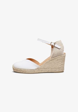 Espadrilla blanca con cuña, tacón de yute tejido, punta cerrada, correa en el tobillo y sección trasera texturizada con cierre de hebilla.