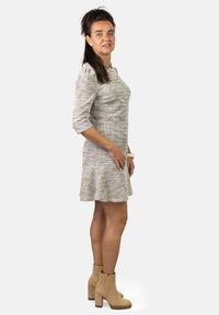 Vestido gris texturizado con mangas tres cuartos y dobladillo acampanado, combinado con botas de tobillo beige que tienen un tacón robusto y un detalle sutil.