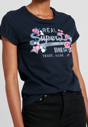 Navy cotton t-shirt featuring a rounded neckline, rolled short sleeves, and floral embroidery with "Superdry" logo in silver and pink accents.