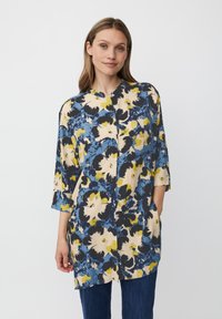 Bloemen tuniek in blauw, geel en crèmekleuren met een V-hals en 3/4 mouwen. Heeft een comfortabele pasvorm en zijzakken. Soepele stof.