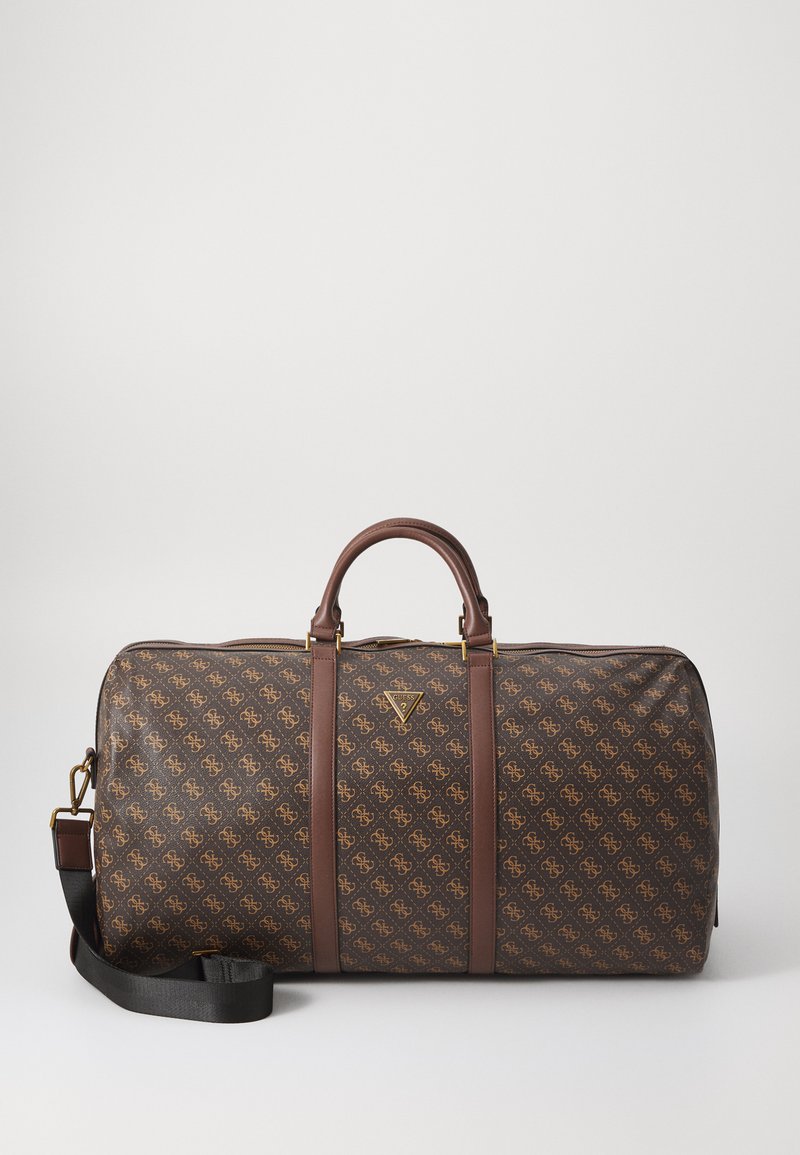 Geantă de duffel din material maro, cu accesorii aurii, curele din piele și un model cu logo. Dispune de o curea de umăr detașabilă și închidere cu fermoar.