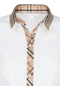 Bílá košile s límečkem v kostkovaném vzoru v béžové a černé barvě. Přední část se zapíná na kulaté bílé knoflíky, látka je hladká a čistá.