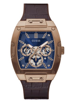 Montre carrée en bronze avec un cadran bleu, trois sous-cadrans, marquages blancs, bracelet en cuir texturé marron et détails matériels accentués.