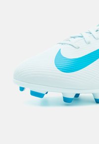 Nike nogometne kopačke s bijelim teksturiranim gornjištem i plavim logotipom te plavim studenicama. Dizajnirane za najbolju prianjanje na travnatim površinama.
