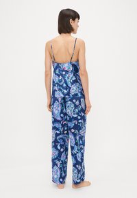 Tamsiai mėlynas pižamų komplektas su paisley raštu, turintis plonas petnešas, laisvai krentančią viršutinę dalį ir plačias kelnes. Glotni medžiagos tekstūra.