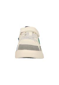 Baskets de sport pour enfant couleur crème avec bande grise sur la pointe, lacets à l’avant et une bride velcro sur le dessus, vue de face.