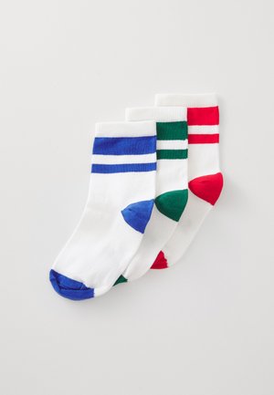Trois chaussettes blanches à la cheville avec des orteils, des talons et deux rayures près du bord en bleu, vert et rouge, empilées sur un fond blanc.