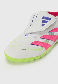 White soccer cleat with neon green sole and pink accents. Features textured material, lacing, and a protective flap with purple detailing.