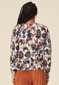 Maglione a maglia con motivo floreale color crema, sfumature di blu, giallo e rosa. Presenta un collo tondo e maniche lunghe, con fascia in vita a coste.