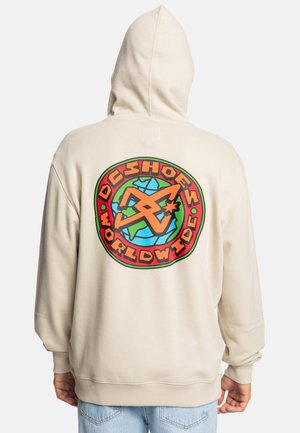 Sweat à capuche beige avec un grand graphique coloré au dos portant le texte "DC Shoes Worldwide" entourant un design de globe et d'étoiles.