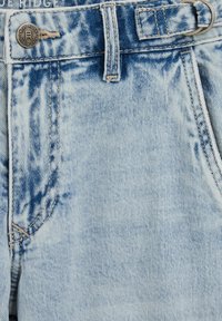 Hämarad helesinised teksapüksid metallnupuga ja vööaasadega. Omavad tikitud taskuid ja tekstuurse pinnaga.