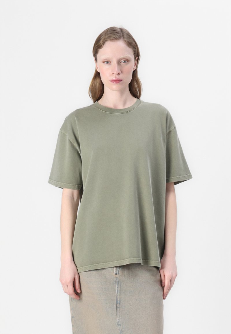 Olive green oversized t-shirt in soft cotton, featuring a round neckline, short sleeves, and stitched detailing, displayed against a white background.