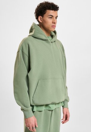 Long-sleeve, light green hoodie made of soft fabric, featuring a front pocket and a relaxed fit with a drawstring hood.