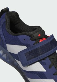 Blå atletiksko med mesh og syntetisk overdel, udstyret med en bred Velcro-rem, tekstureret sål og hvide accenter på siderne.