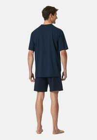 T-shirt en coton bleu marine avec un motif à carreaux, associé à un short bleu marine. Le t-shirt a un col ras du cou et des manches courtes.