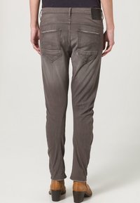 Grå denim skinny jeans med två bakfickor, lätt blekning och en märkesetikett på midjan. Bärs med bruna klackstövlar.