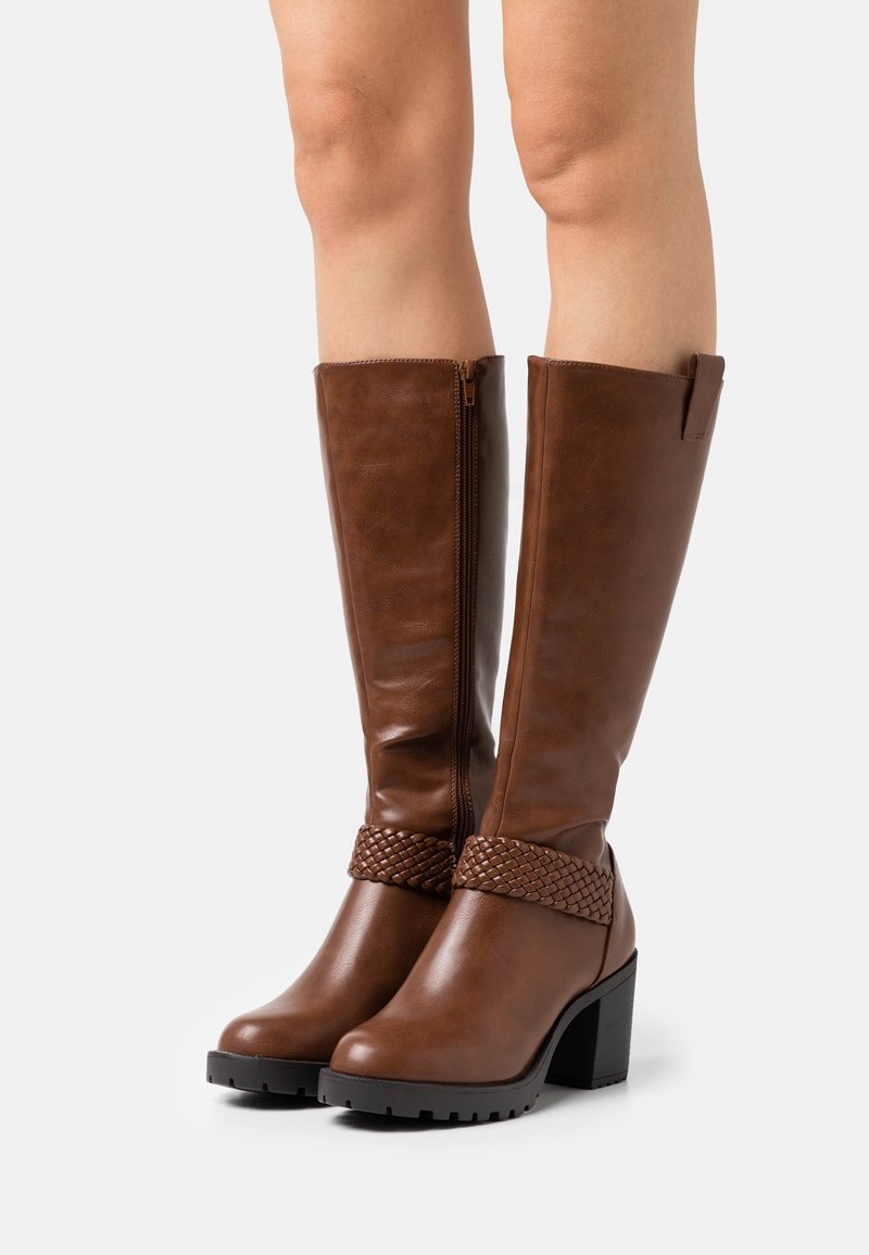 Bruine leren kniehoog laarzen met een gevlochten riem bij de enkel, chunky hak en ritssluiting aan de zijkant. Getextureerde afwerking.