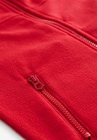 Rote Fleecejacke mit einem Reißverschluss vorne, passendem Reißverschluss-Griff, glatter Textur und langen Ärmeln.
