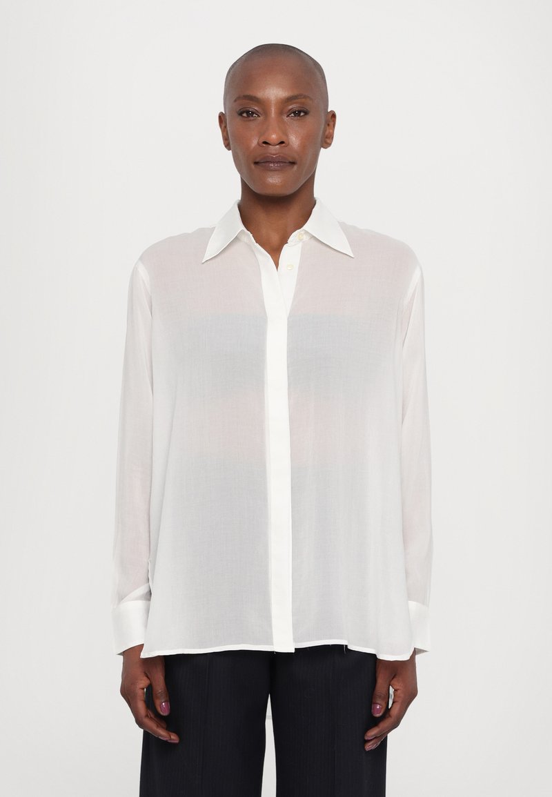 White long-sleeve shirt made of sheer fabric with a pointed collar, button front, and contrasting white cuffs. Soft texture with a relaxed fit.