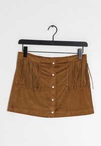 Hnědá semišová mini sukně s třásněmi na obou stranách, s předním zapínáním na knoflík a hladkým povrchem. Visí na černém ramínku.